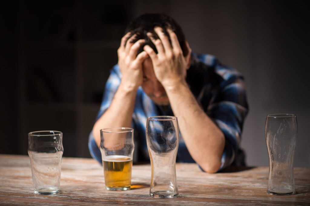 man with an addiction to alcohol near empty beer glasses